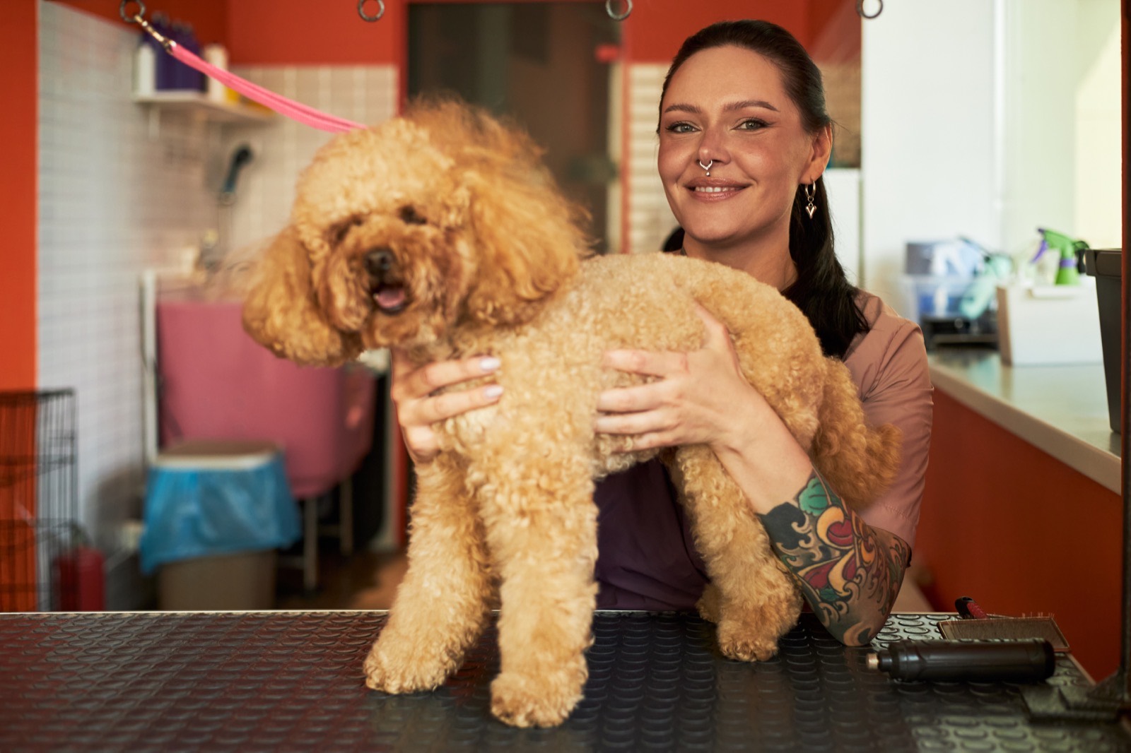 Morgan, a Paws & Suds groomer, smiling with a dog